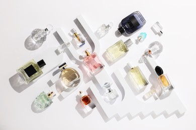 Photo of Different luxury perfumes on white background, flat lay