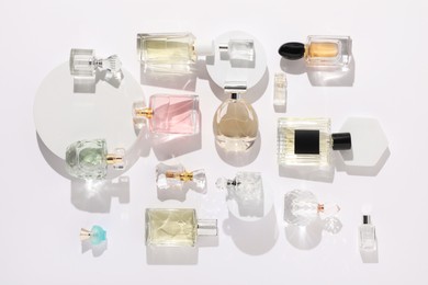 Photo of Different luxury perfumes on white background, flat lay