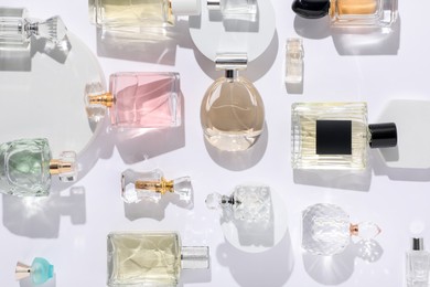 Photo of Different luxury perfumes on white background, flat lay