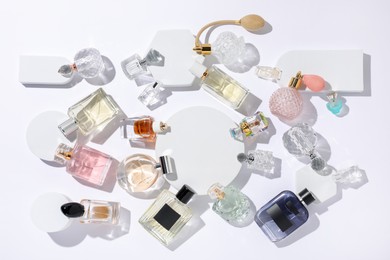 Photo of Different luxury perfumes on white background, flat lay