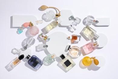 Photo of Different luxury perfumes on white background, flat lay