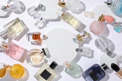 Photo of Different luxury perfumes on white background, flat lay