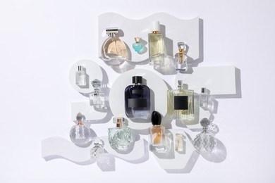 Photo of Different luxury perfumes on white background, flat lay