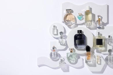 Photo of Different luxury perfumes on white background, flat lay. Space for text