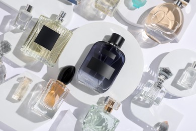Photo of Different luxury perfumes on white background, flat lay