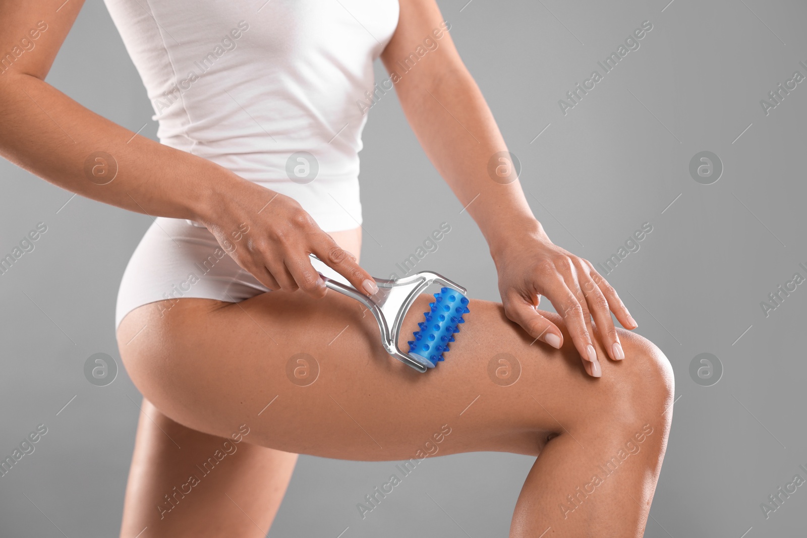 Photo of Woman doing anti cellulite massage with roller on grey background, closeup