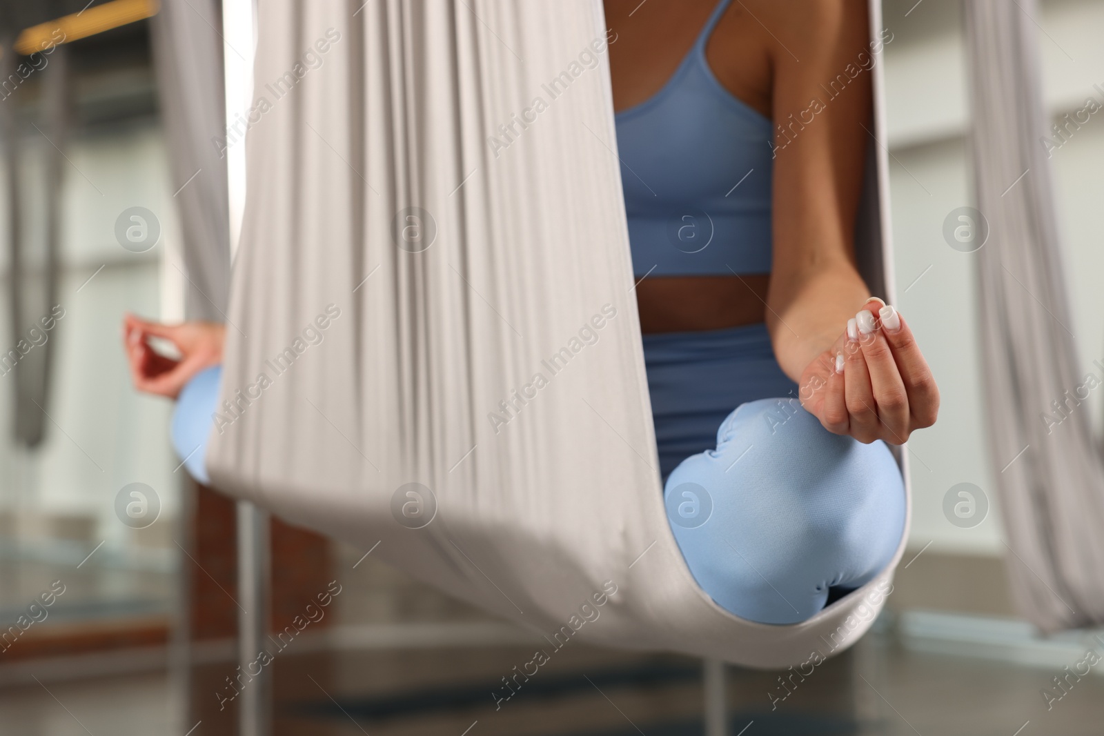 Photo of Woman meditating in fly yoga hammock indoors, closeup