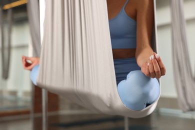 Woman meditating in fly yoga hammock indoors, closeup