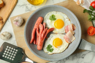 Photo of Tasty brunch. Fried eggs, sausages, bacon and other products on white marble table, flat lay