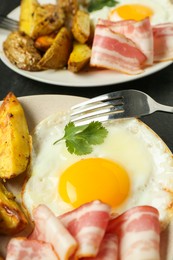 Photo of Tasty brunch. Fried egg, potato, bacon and fork on dark table, closeup