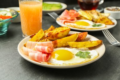 Photo of Tasty brunch. Fried egg, potato and bacon on dark textured table, closeup