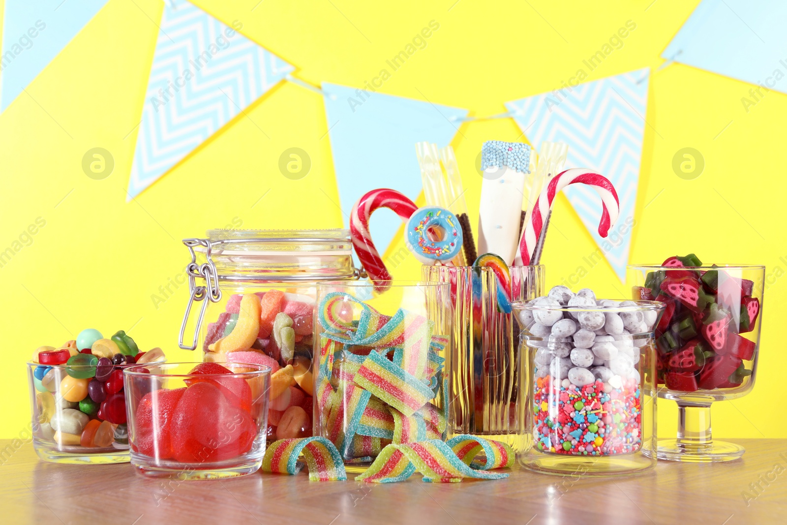 Photo of Candy bar. Many different sweets on wooden table against yellow background