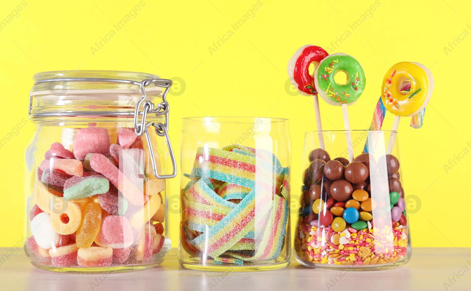 Photo of Candy bar. Many different sweets on white table against yellow background