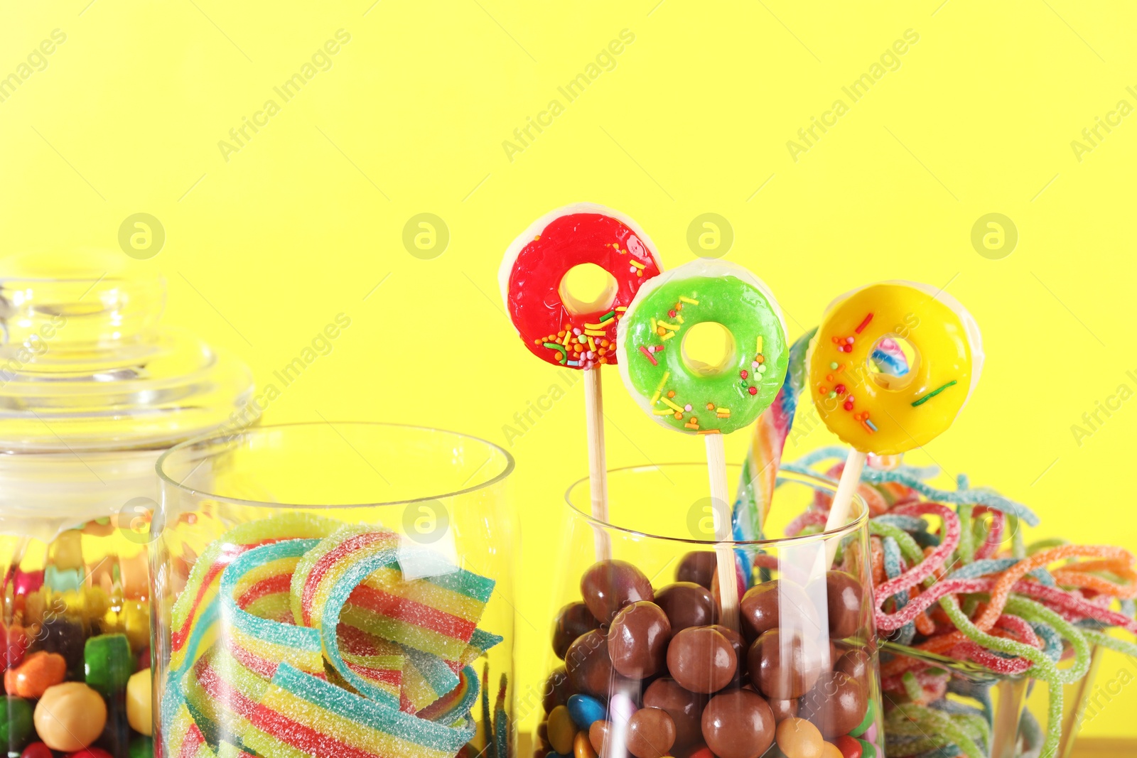 Photo of Candy bar. Many different sweets against yellow background, closeup. Space for text