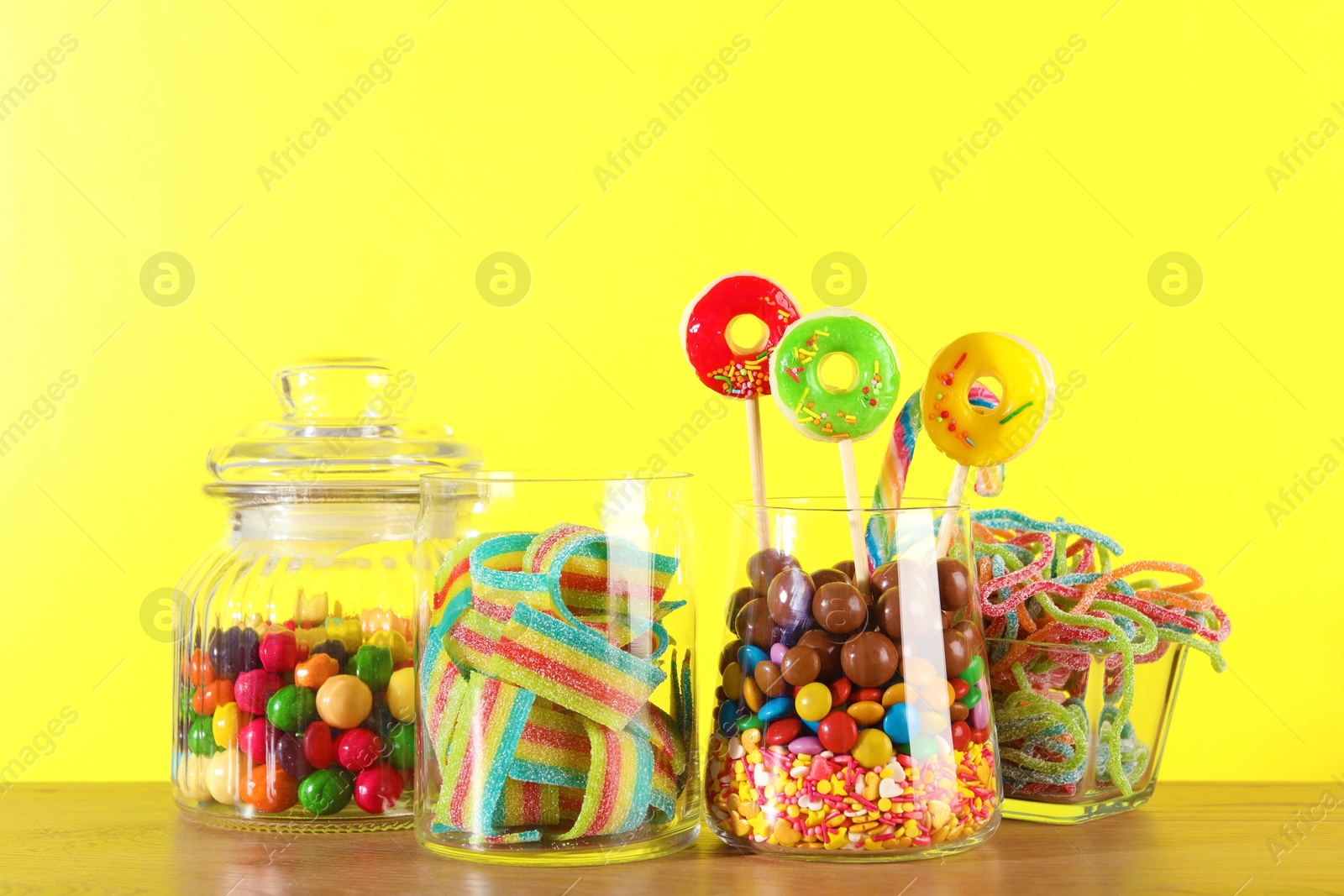 Photo of Candy bar. Many different sweets on wooden table against yellow background