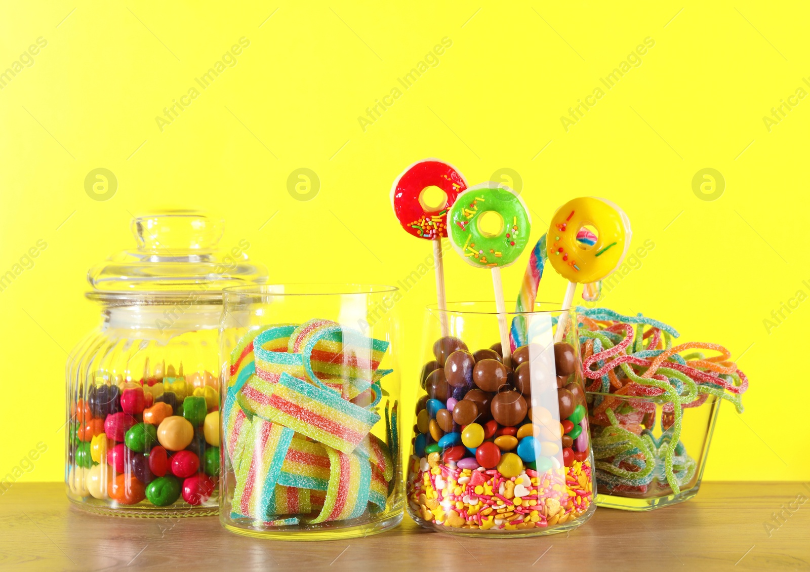 Photo of Candy bar. Many different sweets on wooden table against yellow background