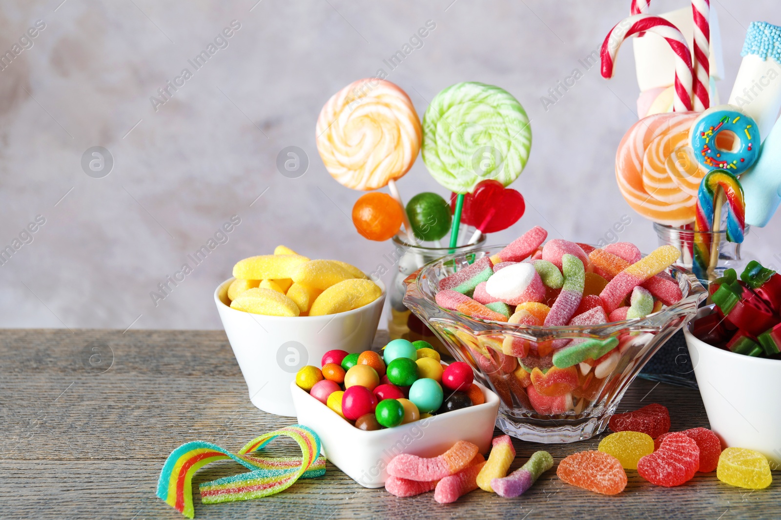 Photo of Candy bar. Many different sweets on wooden table against grey background. Space for text