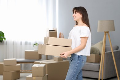 Moving day. Happy woman with cardboard boxes in her new home