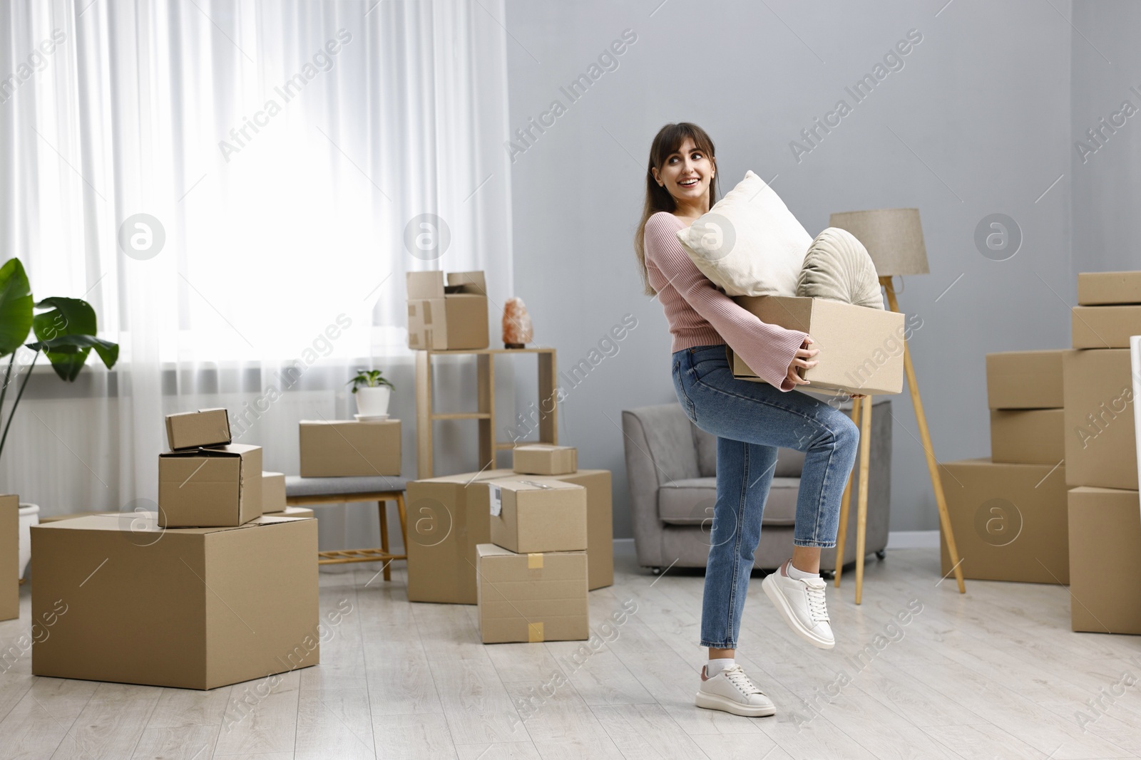 Photo of Moving day. Happy woman with her belongings in new home