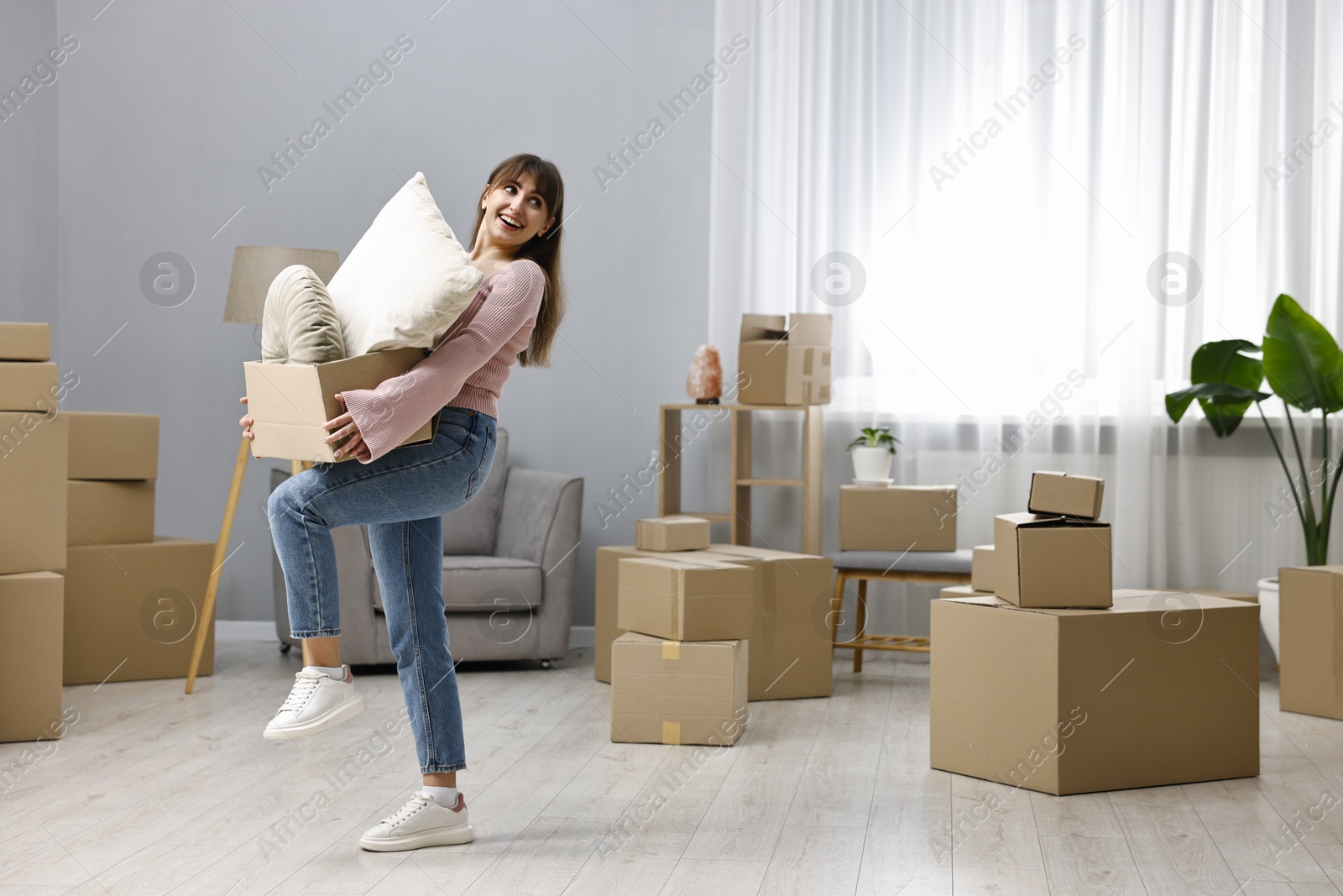 Photo of Moving day. Happy woman with her belongings in new home