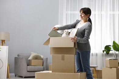 Photo of Moving day. Happy woman unpacking box in her new home