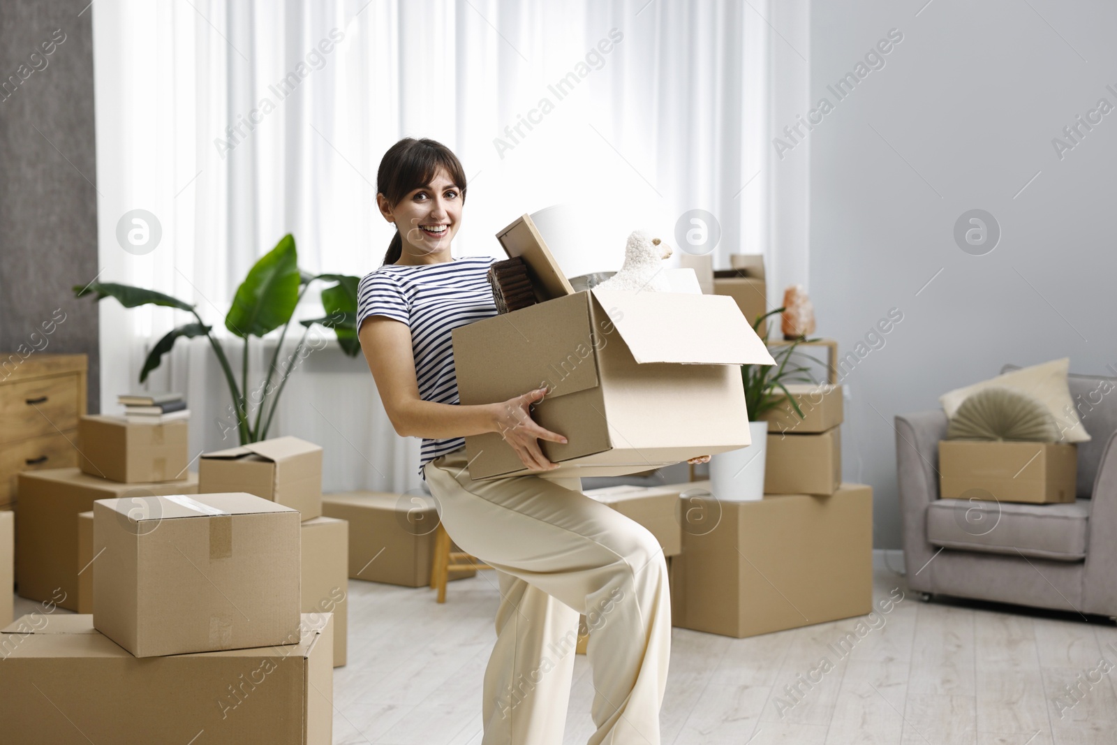 Photo of Moving day. Happy woman with her belongings in new home