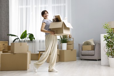 Moving day. Happy woman with her belongings in new home