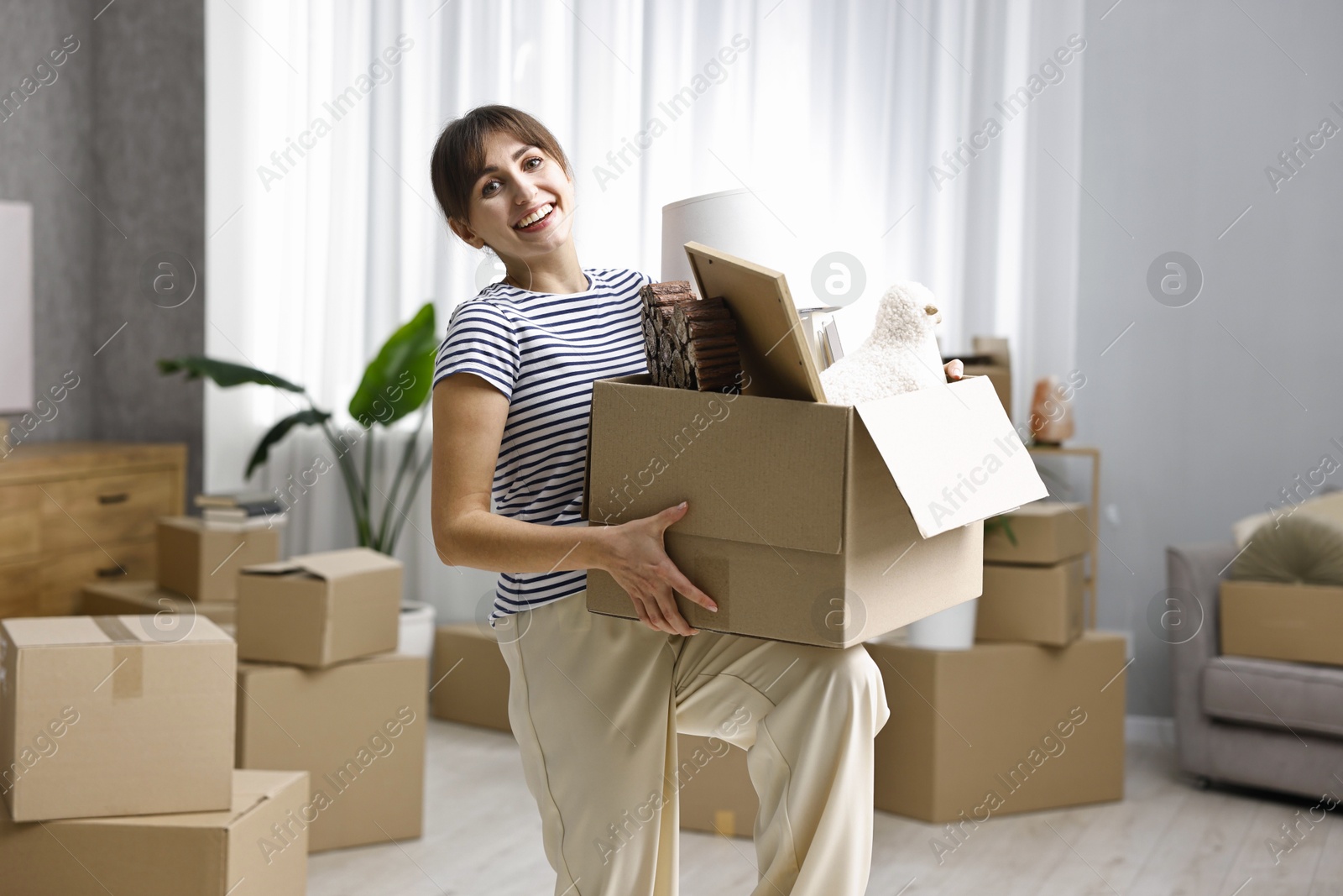 Photo of Moving day. Happy woman with her belongings in new home