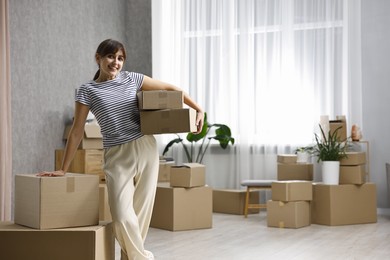 Moving day. Happy woman with cardboard boxes in her new home, space for text