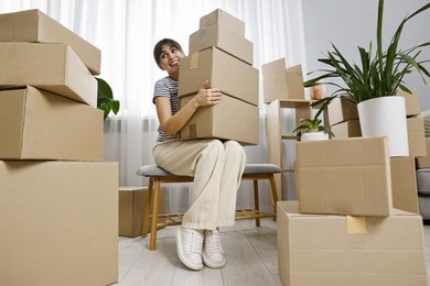 Photo of Moving day. Happy woman with cardboard boxes in her new home