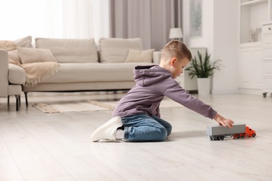 Photo of Little boy playing with toy car at home. Space for text