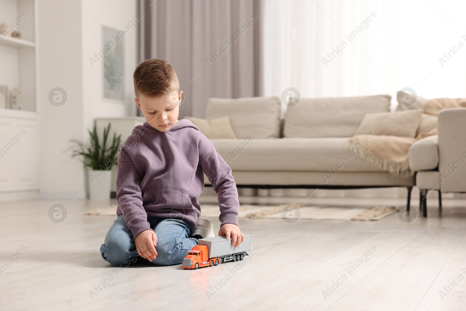 Photo of Little boy playing with toy car at home. Space for text