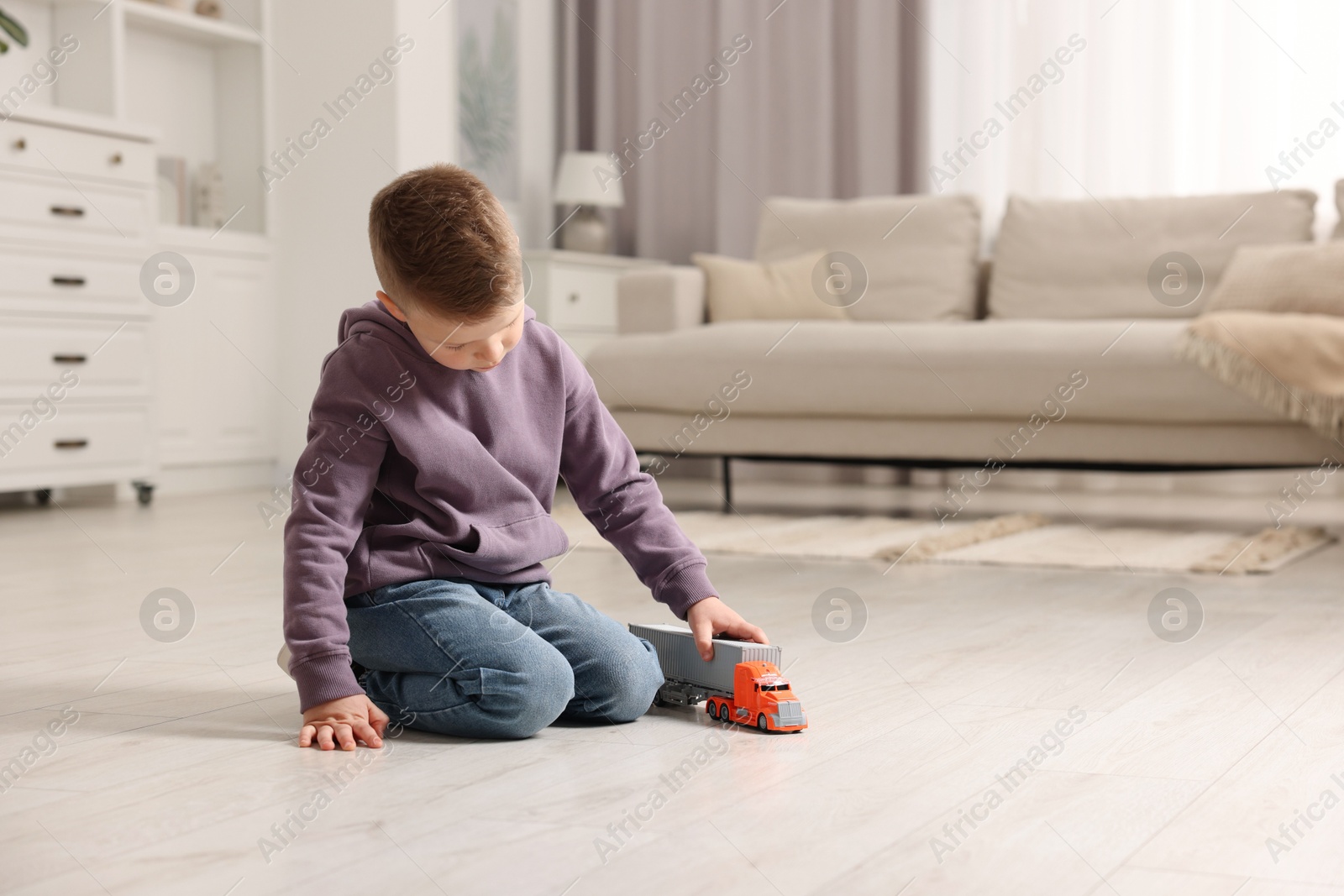 Photo of Little boy playing with toy car at home. Space for text