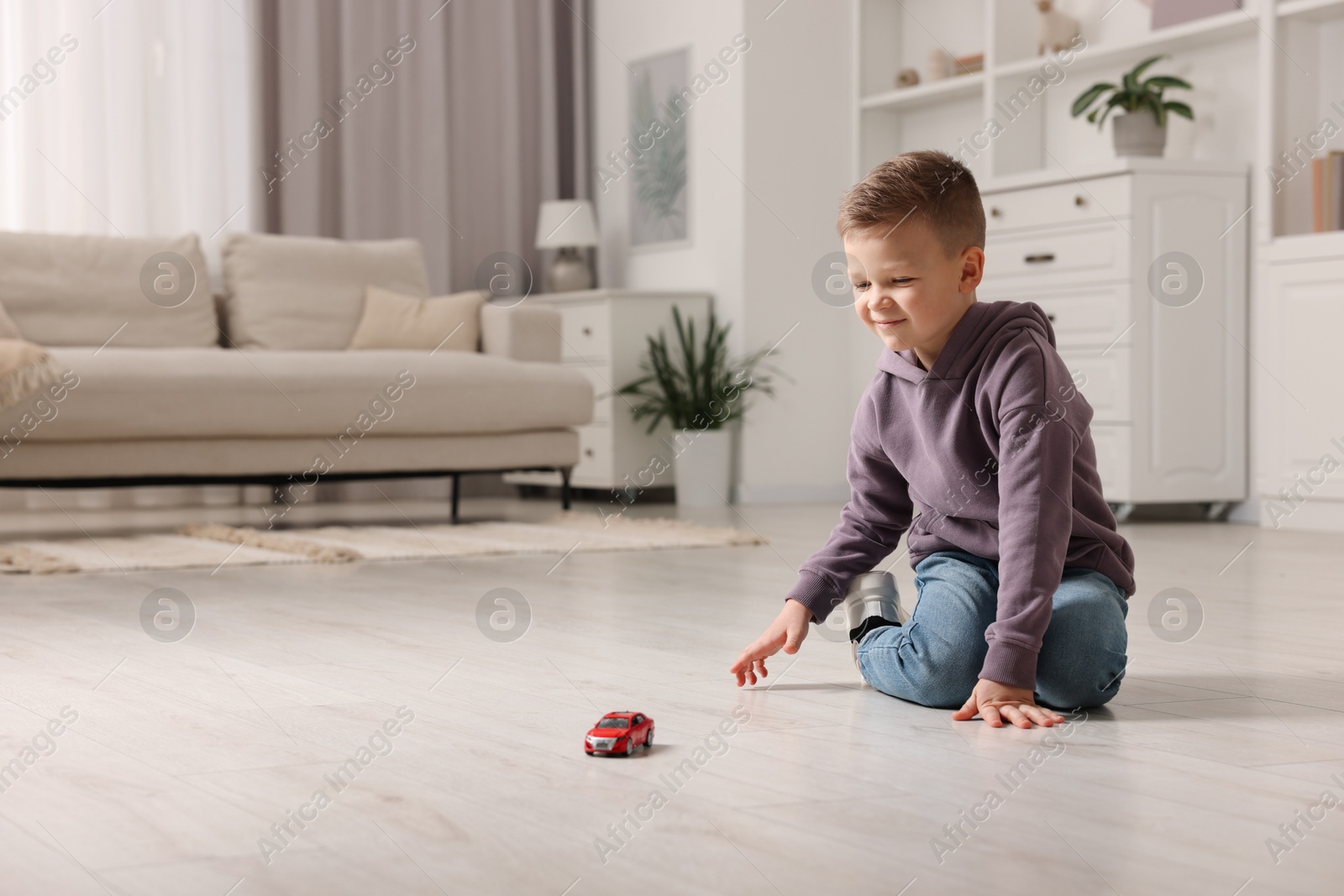 Photo of Little boy playing with toy car at home. Space for text