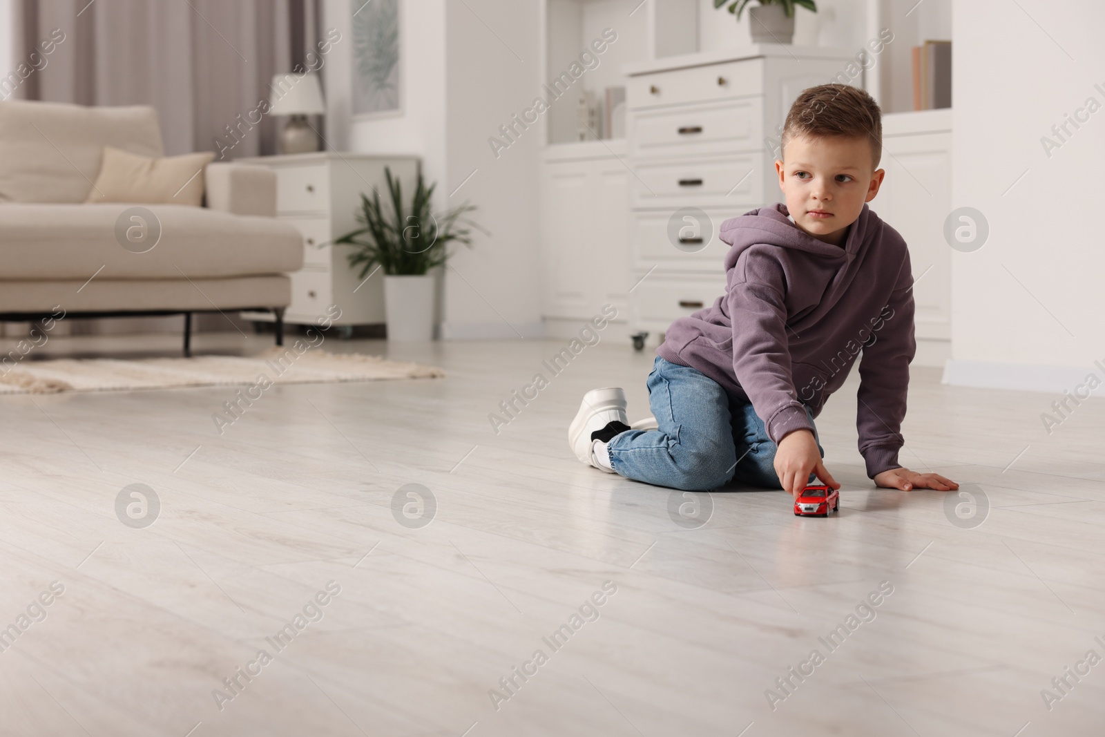 Photo of Little boy playing with toy car at home. Space for text