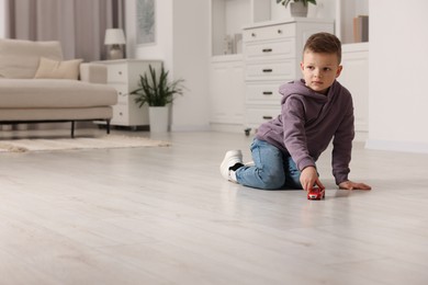 Little boy playing with toy car at home. Space for text