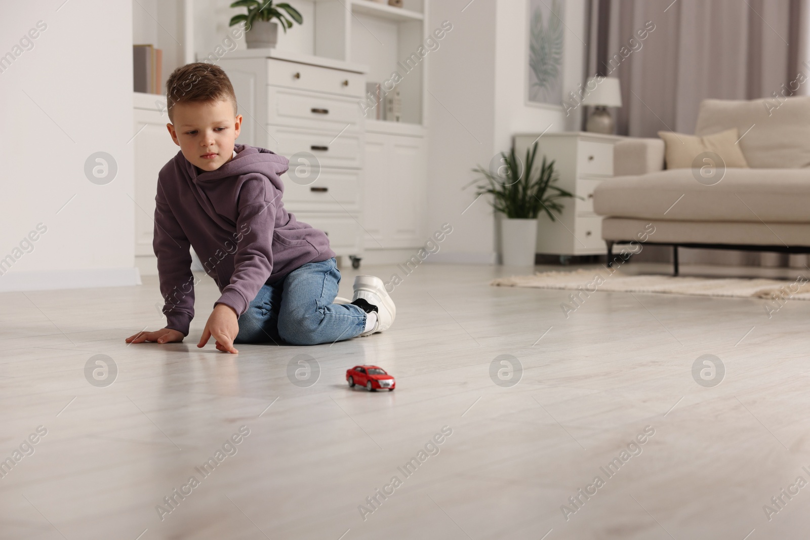 Photo of Little boy playing with toy car at home. Space for text