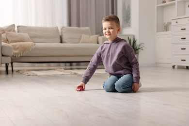 Photo of Little boy playing with toy car at home. Space for text