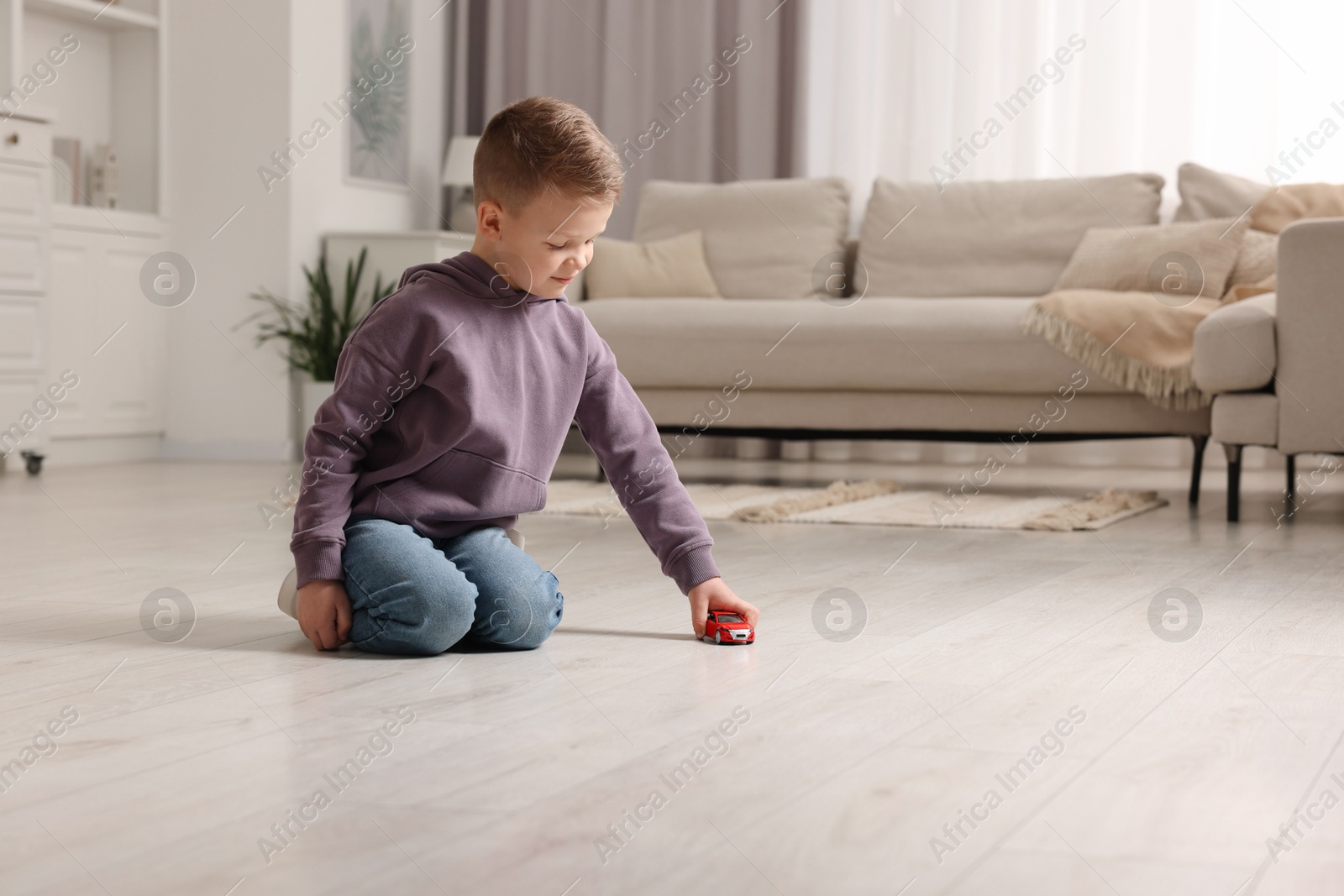 Photo of Little boy playing with toy car at home. Space for text