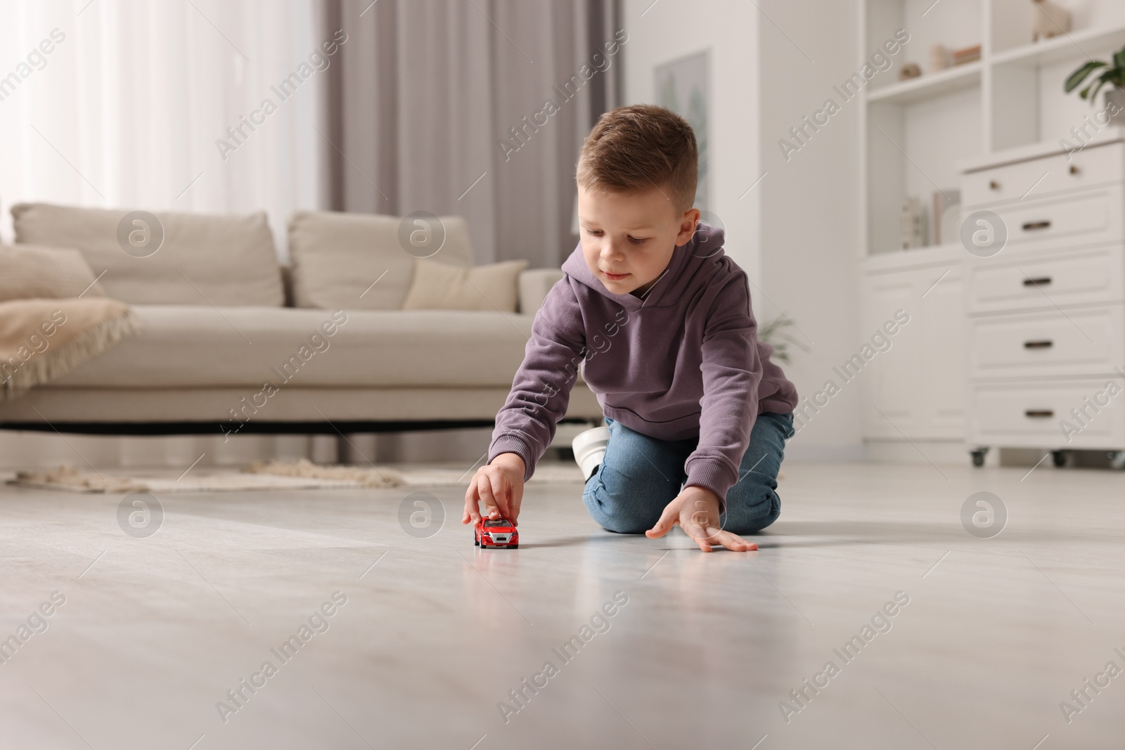 Photo of Little boy playing with toy car at home. Space for text