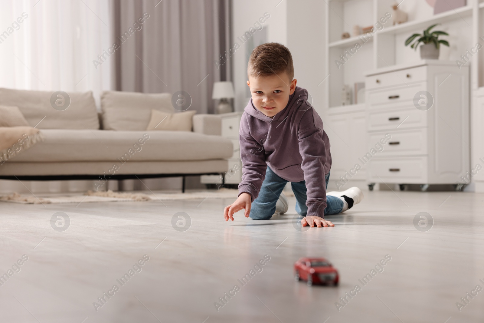 Photo of Little boy playing with toy car at home. Space for text