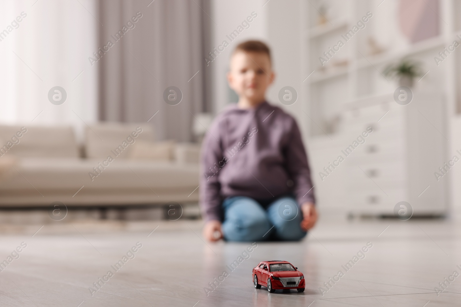 Photo of Little boy playing with toy car at home, selective focus