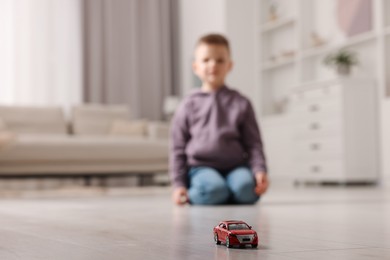 Photo of Little boy playing with toy car at home, selective focus