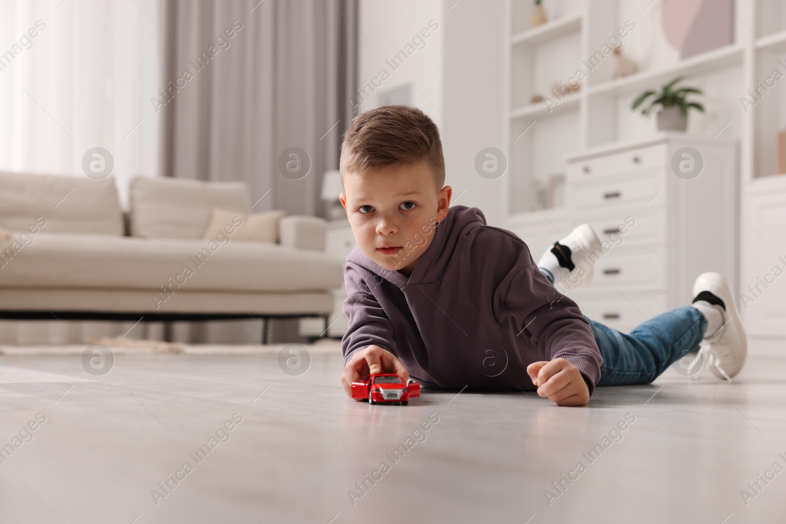 Photo of Little boy playing with toy car at home. Space for text