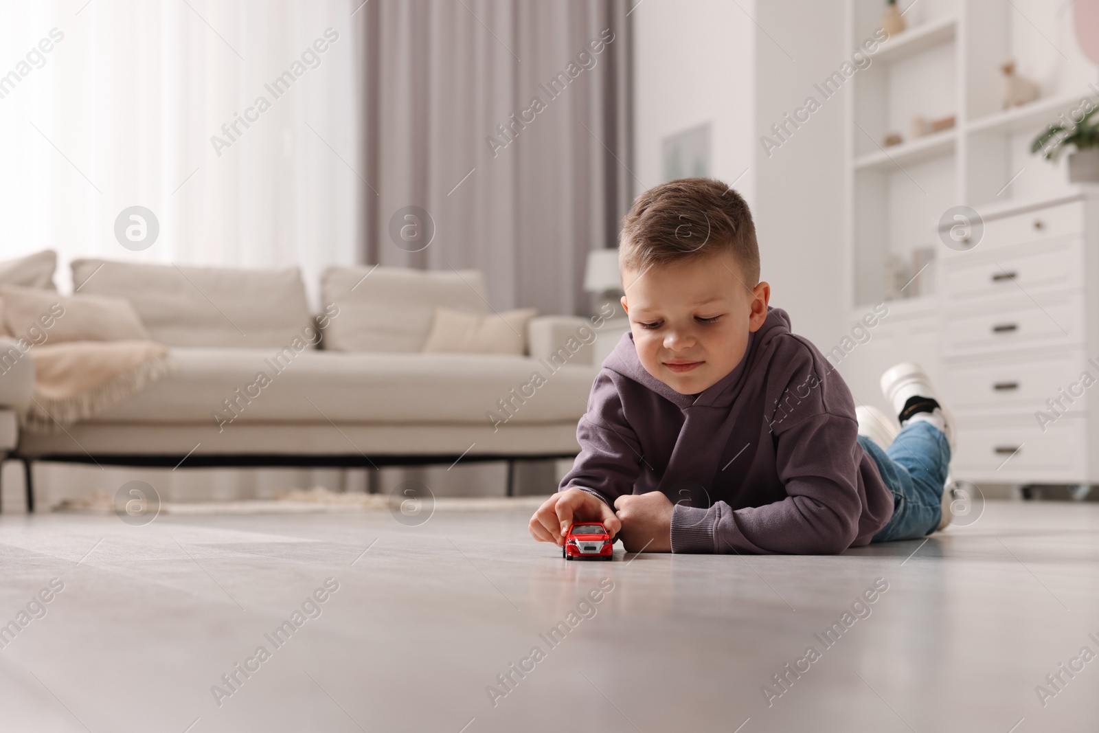 Photo of Little boy playing with toy car at home. Space for text