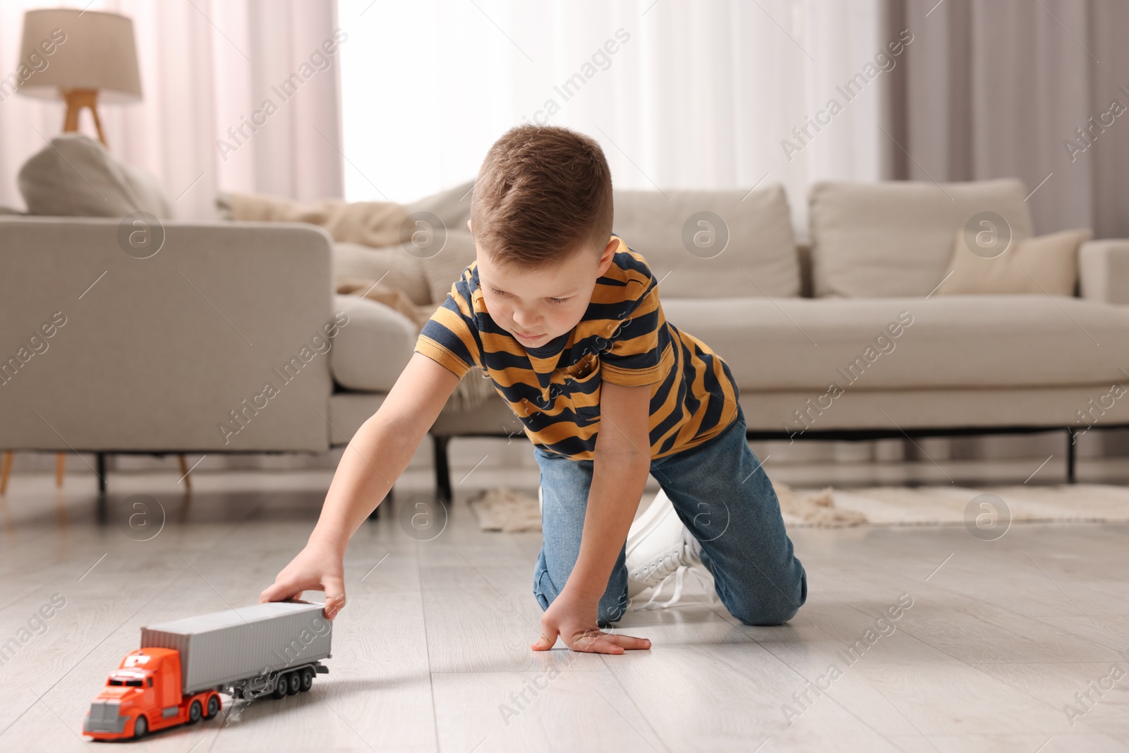 Photo of Little boy playing with toy car at home