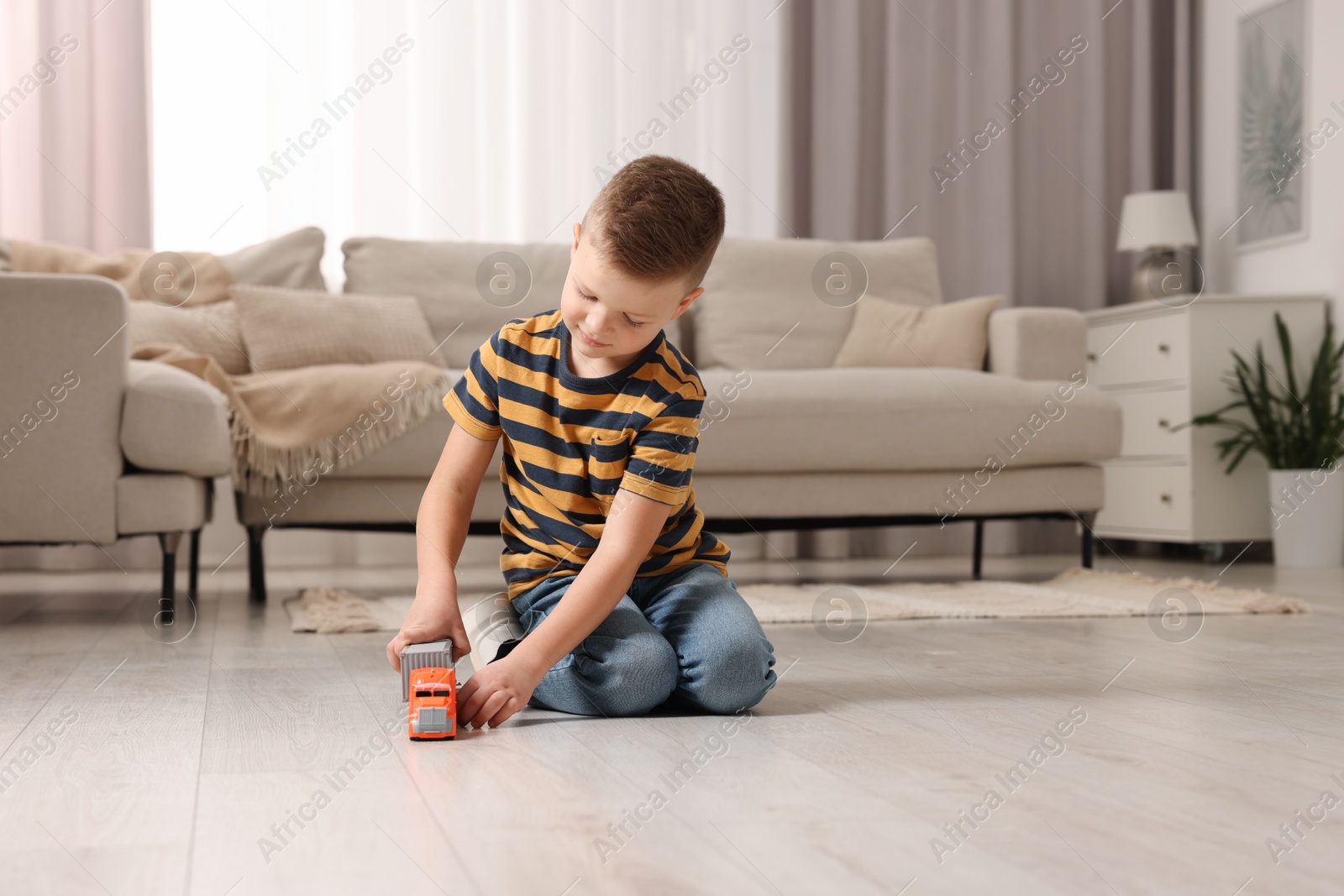 Photo of Little boy playing with toy car at home