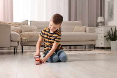 Photo of Little boy playing with toy car at home