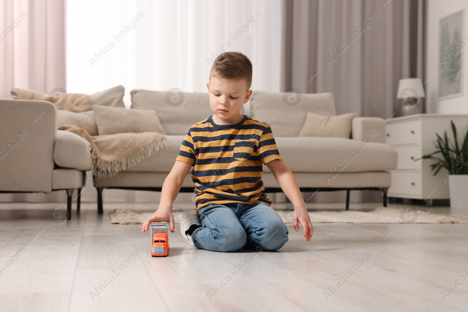 Photo of Little boy playing with toy car at home