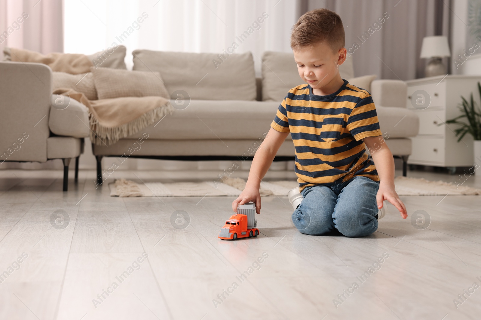 Photo of Little boy playing with toy car at home. Space for text